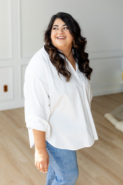 Marissa Martinez in a white top and blue jeans smiling looking off to the side
