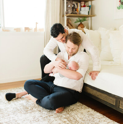 LGBTQ couple hold and look at their newborn baby, captured by Tevi Hardy, San Francisco