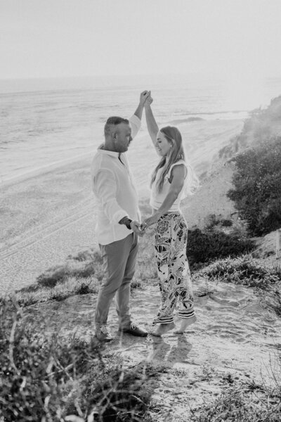 black and white image couple dancing on cliffside