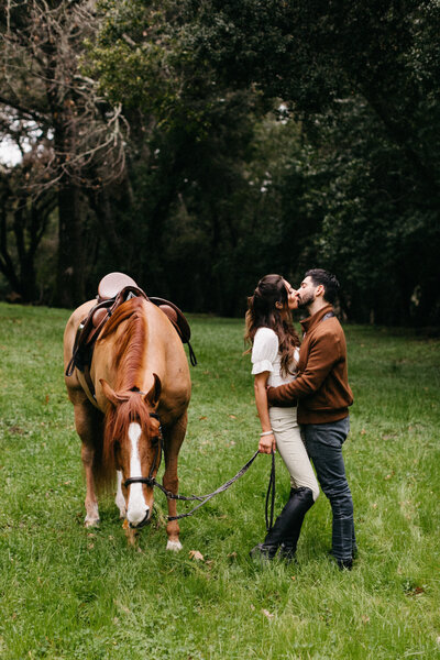 girl kissing boy with horse standing next to them
