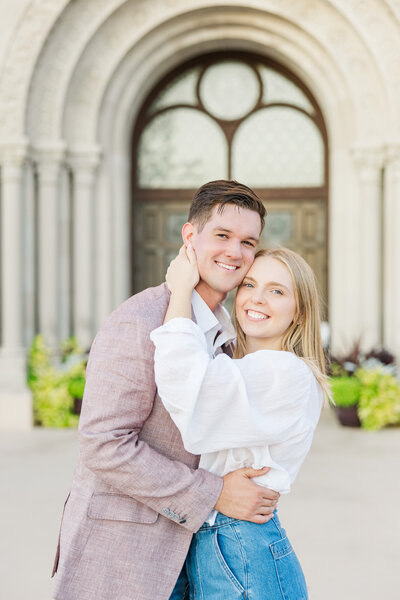 engaged couple hugging in front of a church