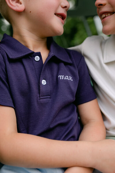 A little boy wearing a navy custom embroidered name polo shirt back to school