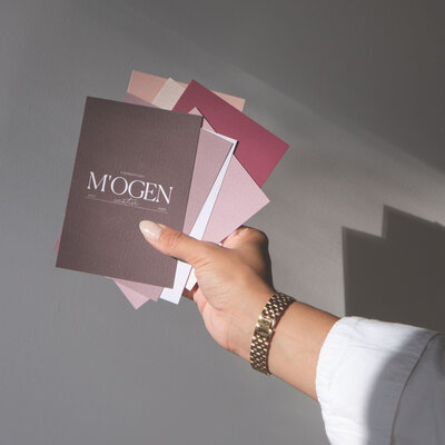 Hand holding colour swatches with M'ogen Creative logo