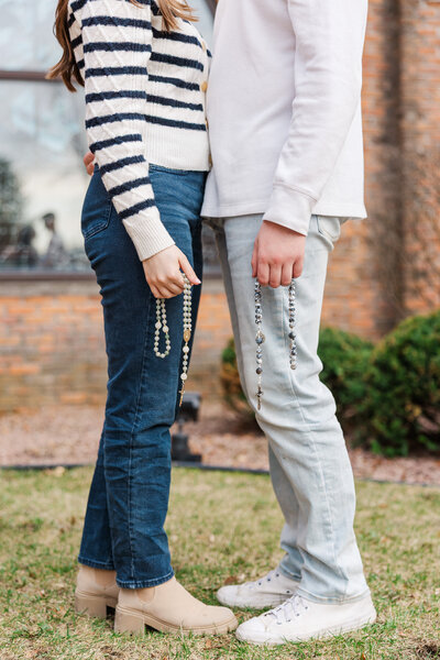 a man and woman facing each other while holding Catholic rosary beads