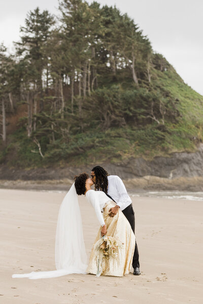 A groom in a blue suit nuzzles into his bride.