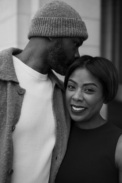 Man kissing woman on the head as she smiles at the camera 