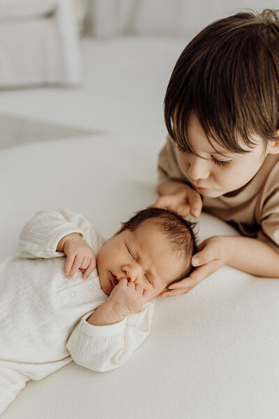A little boy holding his newborn siblings during a newborn photoshoot with christchurch photographer lucy jane