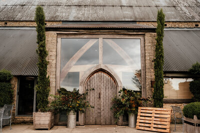 Cripps Barn entrance with rustic autumnal milkchurns 