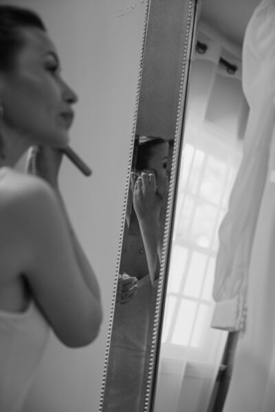 Payton touching up her wedding day makeup. Black and white.