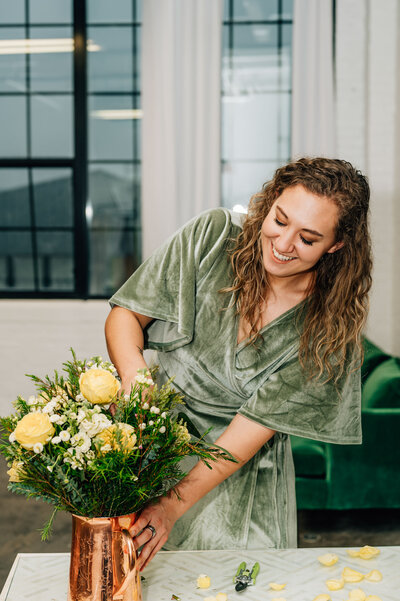 Pittsburgh wedding florist Heavenly Blooms adjusting a floral arrangement centerpiece in a copper vase