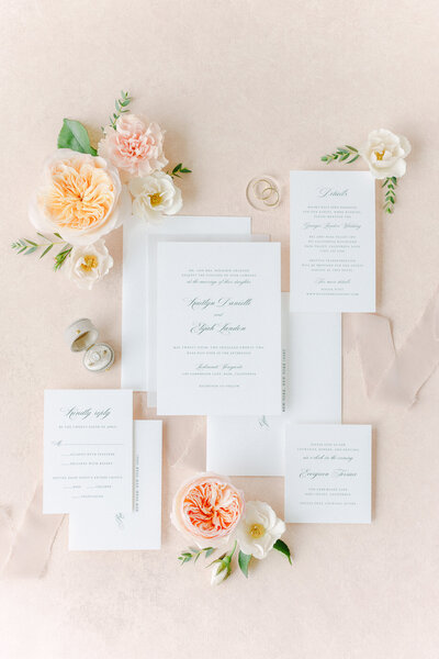 An invite suite is styled with garden roses and ribbons.