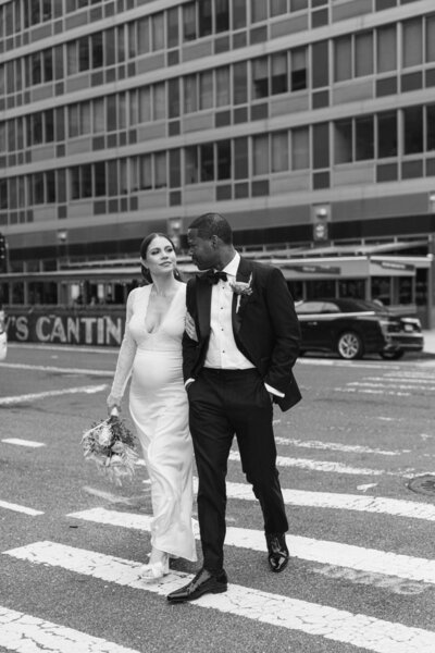 A bride and groom walk across the street in New York City as they make their way to their wedding reception.
