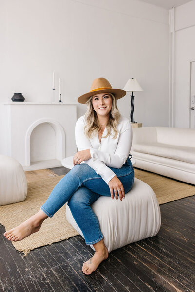 Calgary Realtor Leigh Kormos sitting on an off-white chair