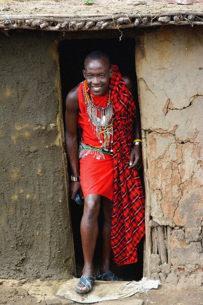 Maasai man in traditional attire standing in a doorway in Kenya.