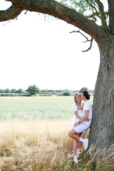 couple-standing-under-tree-at-engagement-shoot-in-the-cotswolds-by-leslie-choucard-photography