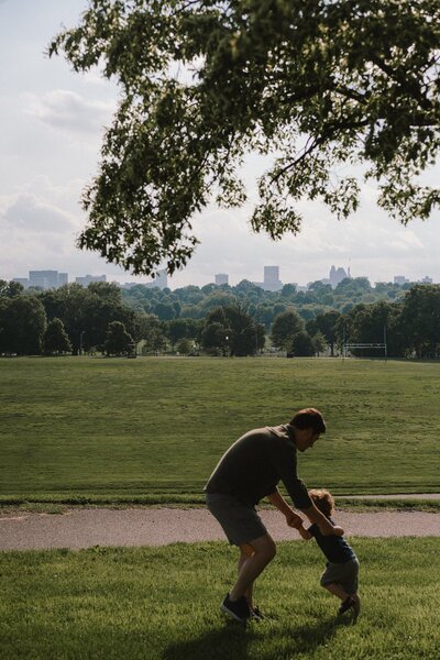 pose of dad playing with son in a field in harsh light by Charlottesville family photographer Leah  O'Connell