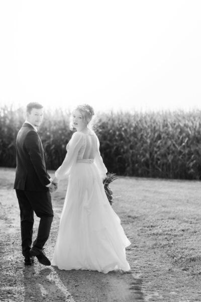 Bride with ginger hair walking in sunlight with groom hand in hand