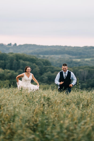 bride and groom run through farm field wisconsin wedding