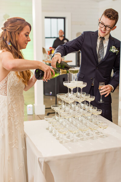 Wedding photo in Banner Elk, NC of a bride and groom pouring champagne into a champagne tower.