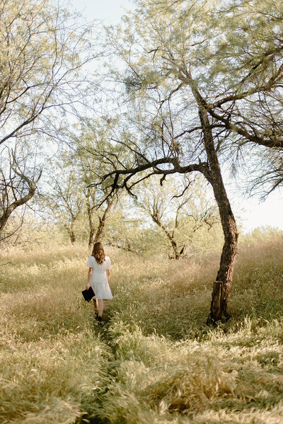 Senior girl walking through grass at the salt river