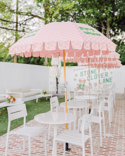 Outdoor photo of white tables and chairs with pink umbrellas