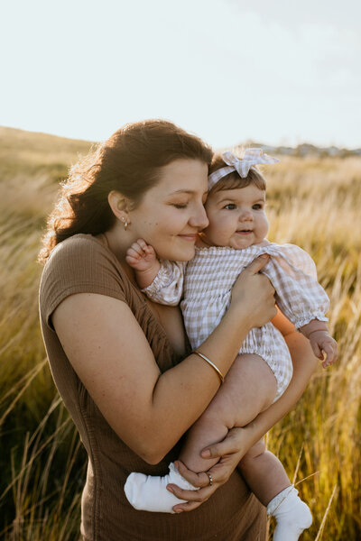 Tender moment of a mother holding her baby daughter in a warm, glowing light.