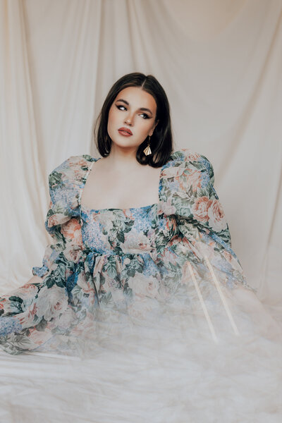 woman in floral gown by window