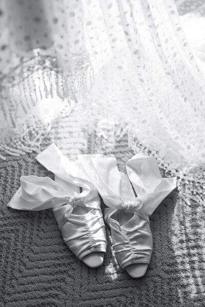 Wedding shoes laying next to a lace veil 