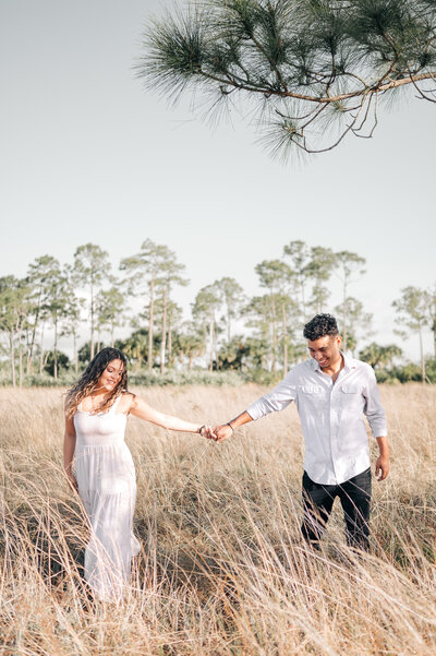 Best Palm beach engagement photographer captures couple holding hands walking through a field