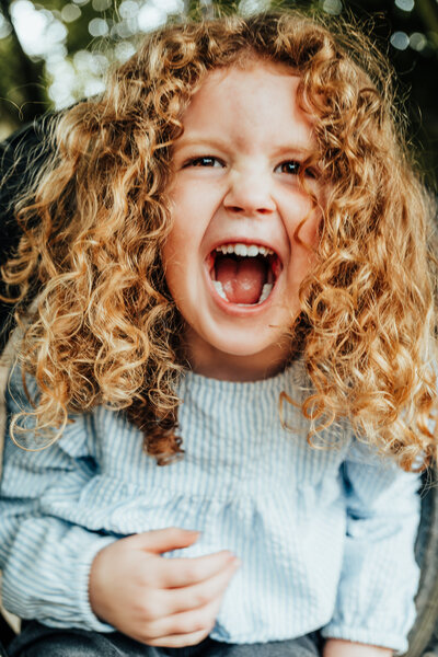 preschooler with curly hair swinging on a tyre