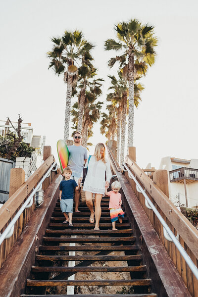 a family walks down the stairs to get to the beach to go surfing in San DIego