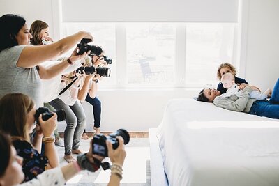 group of female photographers photographing a newborn at home during in person retreat