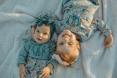 two girls laying on a blanket and smiling