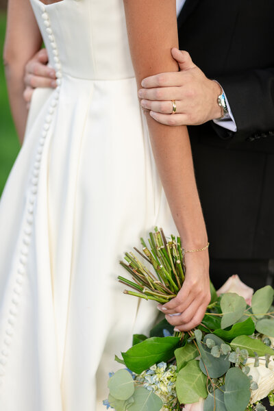 A groom gently holds his bride’s arm as she carries her bouquet, captured by Nathan Sottung Photography at Columbia Country Club in Maryland.