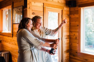 Sisters popping champagne at Washington Airbnb before getting dressed for an elopement near Port Angeles.