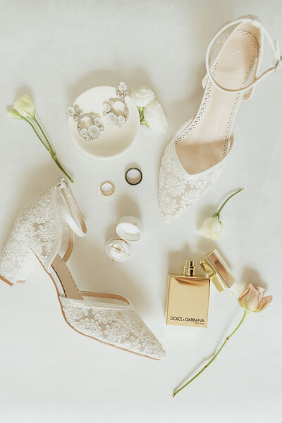 flat lay of wedding shoes, perfume, rings in classic modern style