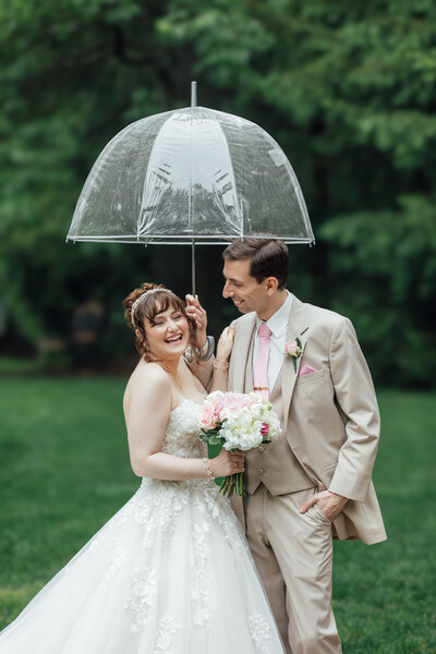 Olde Mill Inn | Groom holding umbrella while bride laughs during wedding photo | Basking Ridge, New Jersey