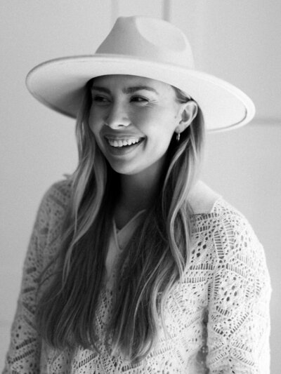 Black and white close up photo of a woman in a hat and sweater