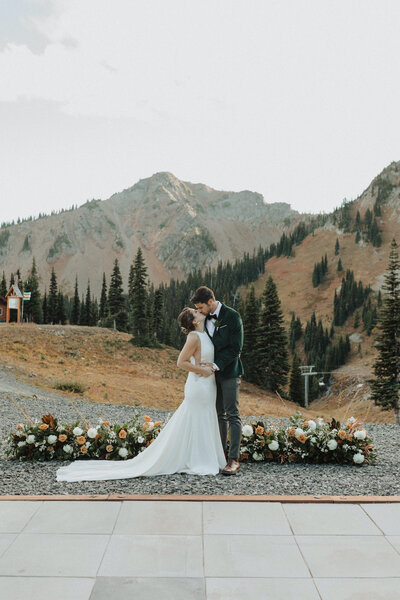 Bride and groom kiss in front of mountains in Washington
