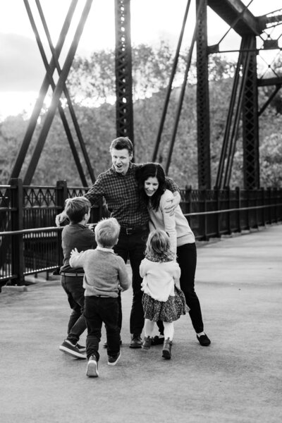 A family with two adults and three children enjoying outdoor time together on a bridge, captured by a talented Pittsburgh photographer.