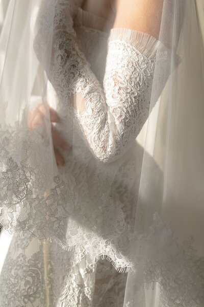 Close-up of lace wedding gown and veil in soft light.
