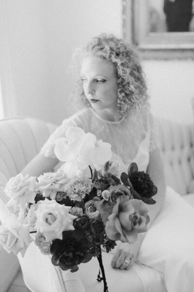 Black & White of Bride sitting gracefully on a white couch for a quiet portrait before her backyard wedding ceremony in Richmond, Virginia, captured in soft natural light.