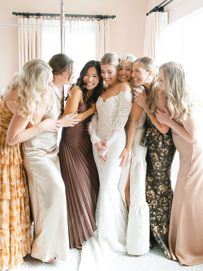 Bride surrounded by her bridesmaids with their arms all around each other