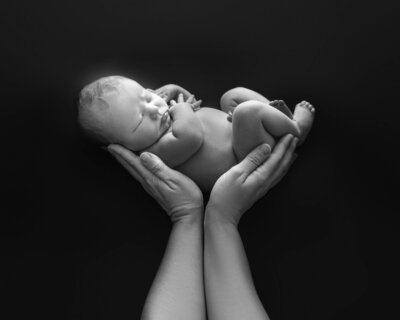 A newborn sleeps in a blue swaddle o a bed of blankets