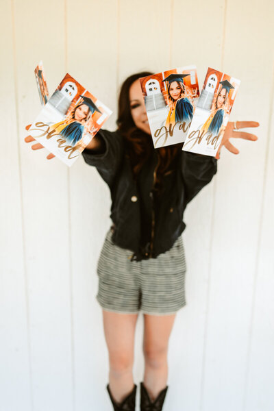 Photographer Annie Bee Photography holding graduation announcements.