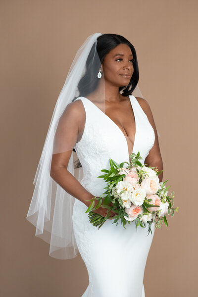 Bride wearing a two layered fingertip length veil and holding a white and blush bouquet