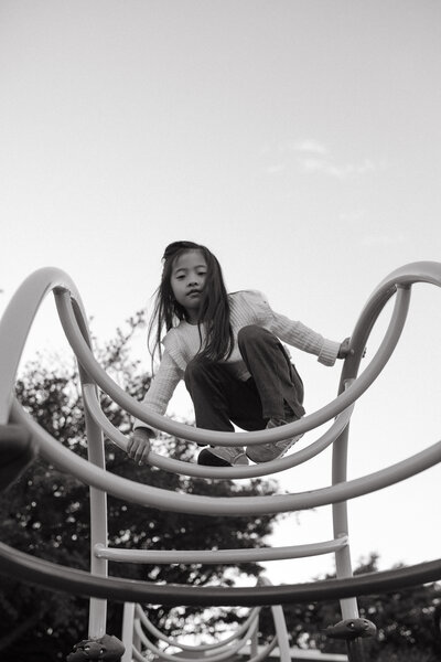 A girl clibing outside and glancing at the camera