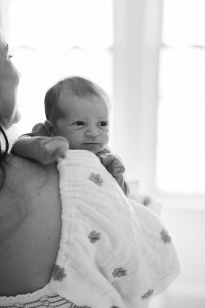 Tiny baby holds on to mom in black and white photo