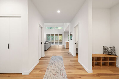 White hallway with wooden floors and a bench