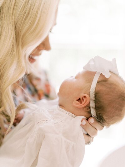 Mom holding newborn with white bow